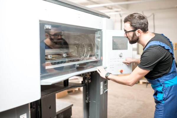 Printing operator working with offset machine at the printing manufacturing